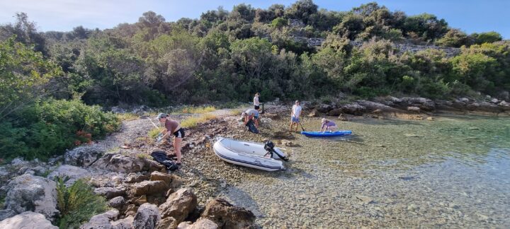 Boote und Crew, die Müll sammelt, in einer Bucht