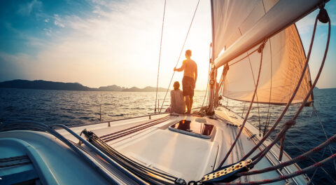 Zwei junge Segler an Bord einer Yacht blicken in den Sonnenuntergang