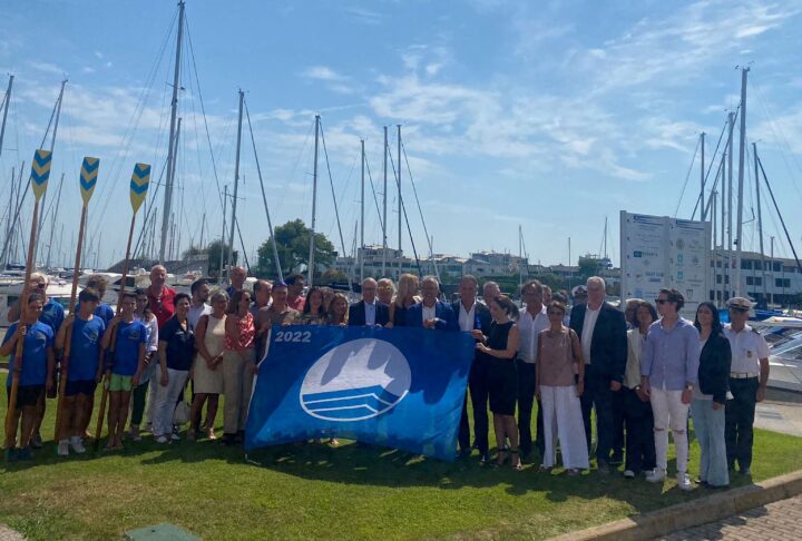Übergabe der Blauen Flagge in der Marina Punta Faro Resort. Dr. Giorgio Ardito (1. v.links) und Paola Piovesana (3. v. links) halten die Flagge zusammen mit Politikern der Region und Mitarbeitenden © FVGMarinas.