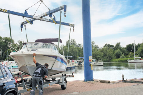 Ein Trailerboot wird in der Marina Müritz mit dem Kran ins Wasser gehoben.