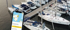 Ein Smartphone mit der ADAC Skipper App vor dem Hintergrund einer Marina in Italien.